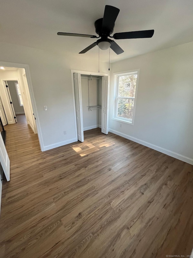 unfurnished bedroom with baseboards, dark wood-style flooring, and a closet