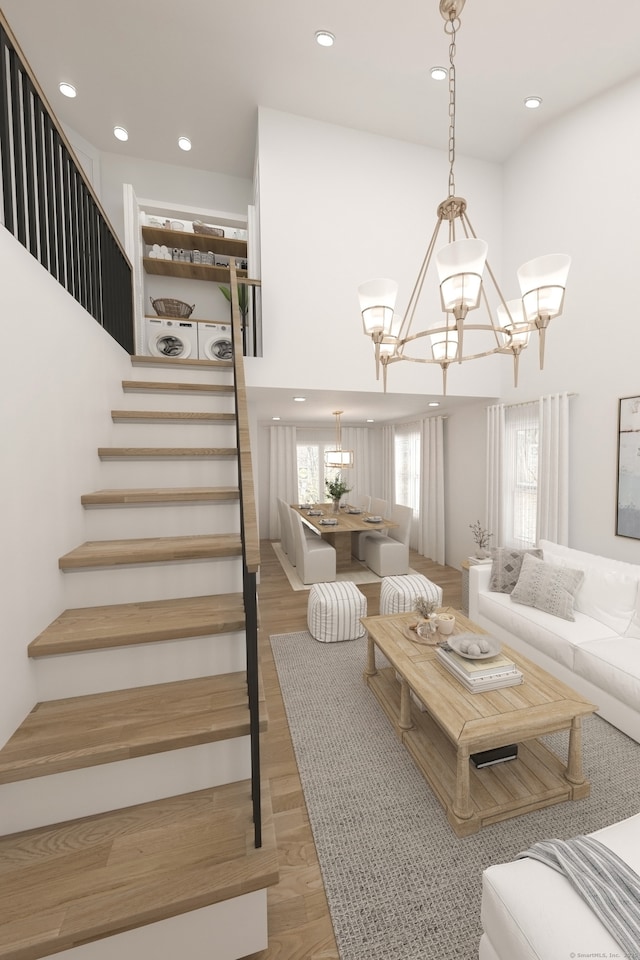 living room featuring a notable chandelier, light wood-type flooring, a towering ceiling, and stairs