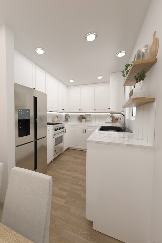 kitchen featuring a sink, stainless steel appliances, open shelves, light wood finished floors, and white cabinets
