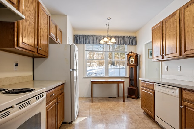 kitchen featuring under cabinet range hood, white appliances, brown cabinets, an inviting chandelier, and pendant lighting