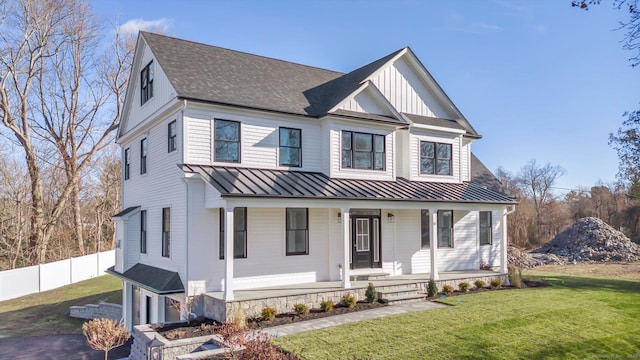 view of front of house featuring a porch, board and batten siding, a standing seam roof, fence, and a front lawn