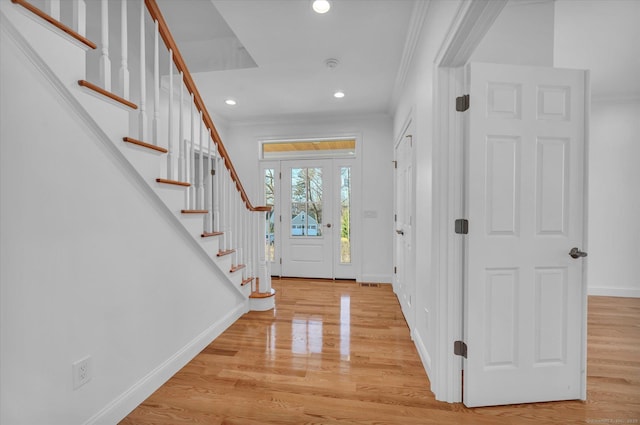 entrance foyer featuring light wood-style floors, baseboards, stairway, and ornamental molding