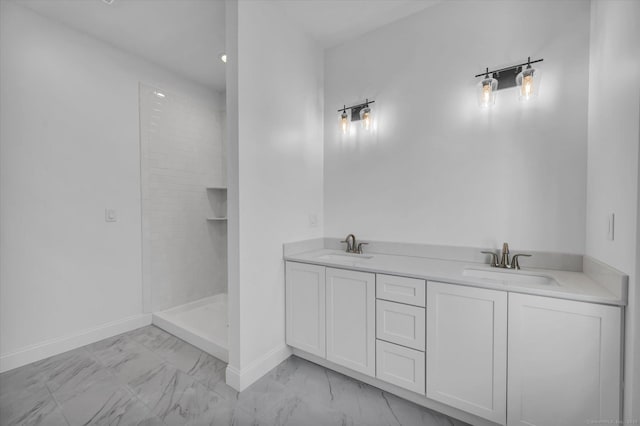 bathroom with marble finish floor, double vanity, a sink, and baseboards