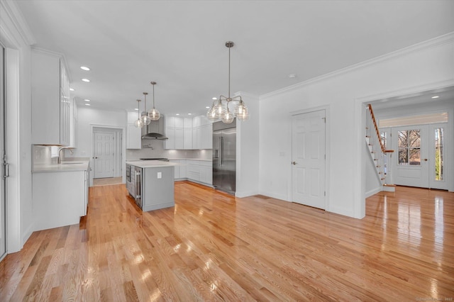 kitchen featuring stainless steel built in refrigerator, light countertops, a kitchen island, and decorative light fixtures