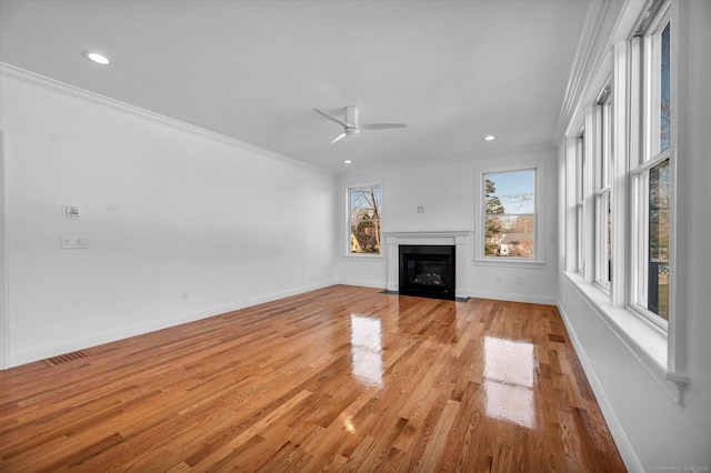 unfurnished living room featuring a fireplace with flush hearth, ornamental molding, light wood-style flooring, and baseboards