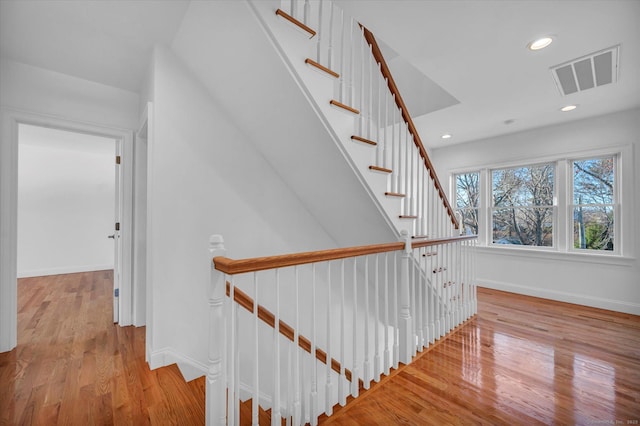 stairway featuring recessed lighting, visible vents, baseboards, and wood finished floors