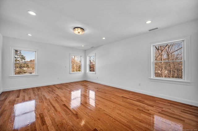 spare room with light wood-type flooring, visible vents, and baseboards