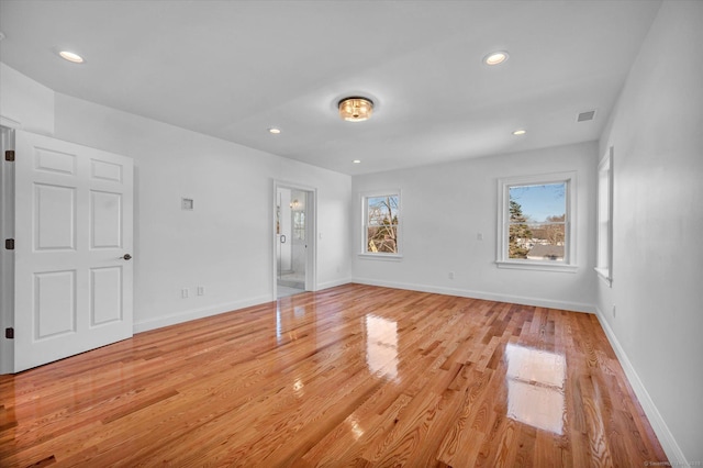 unfurnished room with light wood-style floors, visible vents, and baseboards