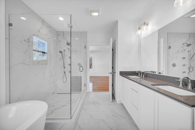 bathroom featuring a soaking tub, marble finish floor, a sink, and a marble finish shower