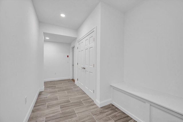 hallway with wood finish floors, recessed lighting, and baseboards