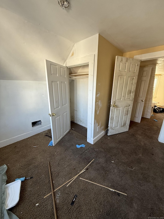 unfurnished bedroom with a closet, baseboards, and lofted ceiling