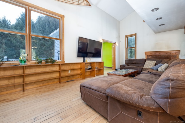 living room featuring light wood-type flooring, a wealth of natural light, and high vaulted ceiling