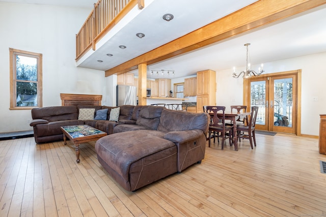 living area featuring light wood finished floors, baseboards, beamed ceiling, a chandelier, and track lighting