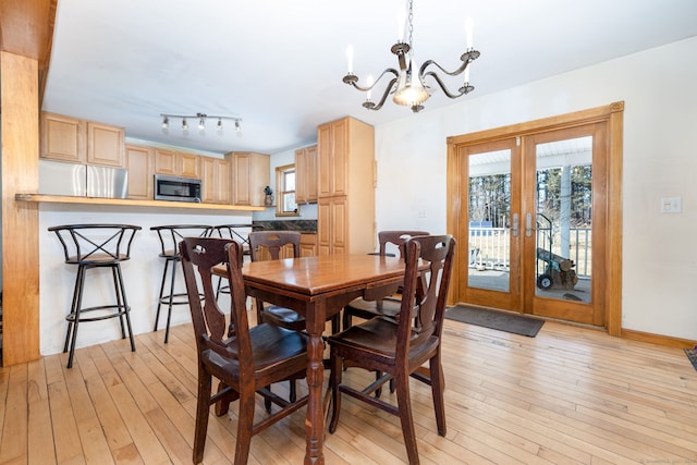 dining area featuring french doors, a notable chandelier, and light wood-style flooring