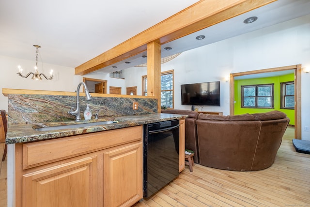 kitchen featuring light wood finished floors, dishwasher, open floor plan, light brown cabinets, and a sink