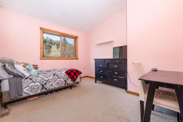 carpeted bedroom featuring lofted ceiling and baseboards