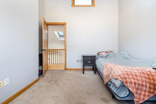 bedroom with carpet floors, a skylight, baseboards, and visible vents