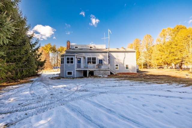 snow covered property with a chimney and a wooden deck