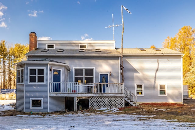 snow covered back of property featuring a chimney and a deck