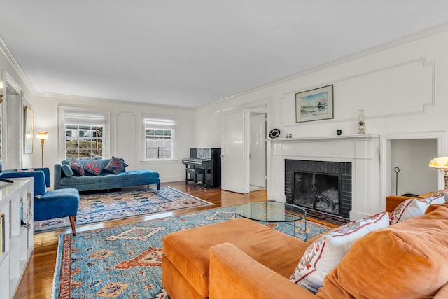 living area featuring a fireplace, crown molding, and wood finished floors