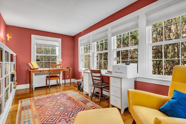 home office with a baseboard radiator, baseboards, wood finished floors, and radiator heating unit