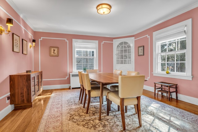 dining area featuring light wood-type flooring, baseboards, ornamental molding, and radiator heating unit