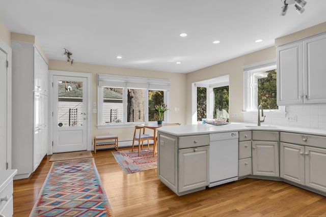 kitchen featuring light wood-style flooring, gray cabinetry, a sink, dishwasher, and baseboard heating