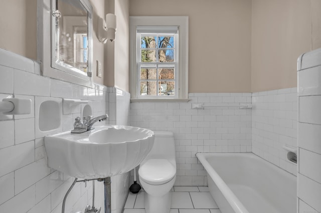 full bathroom with toilet, a tub to relax in, tile patterned floors, tile walls, and a sink