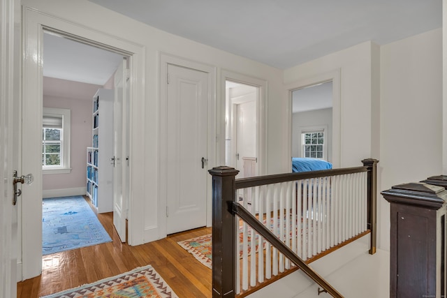 hall with hardwood / wood-style floors, an upstairs landing, and baseboards