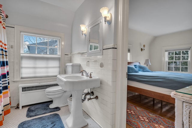 full bathroom with toilet, radiator heating unit, connected bathroom, tile walls, and wainscoting