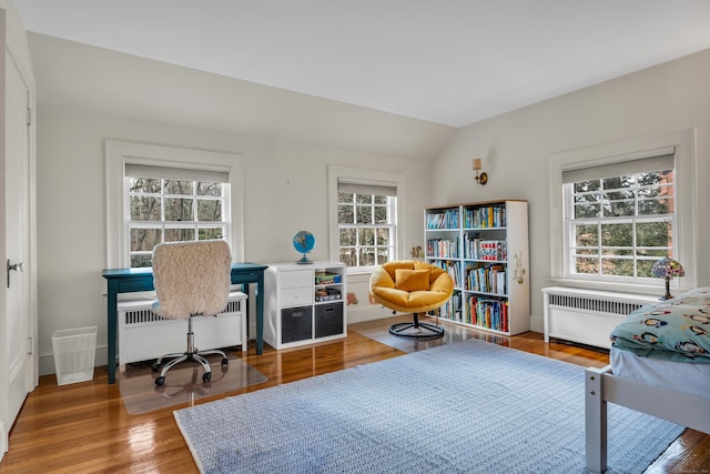 office area featuring baseboards, lofted ceiling, radiator, and wood finished floors