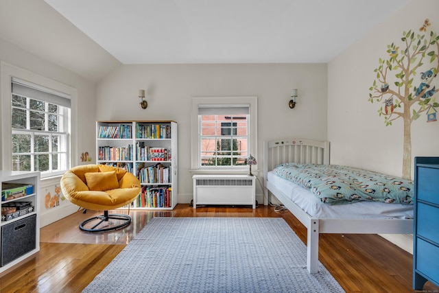 bedroom with multiple windows, radiator, lofted ceiling, and hardwood / wood-style flooring