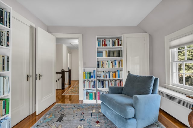 sitting room featuring vaulted ceiling, radiator, and wood finished floors