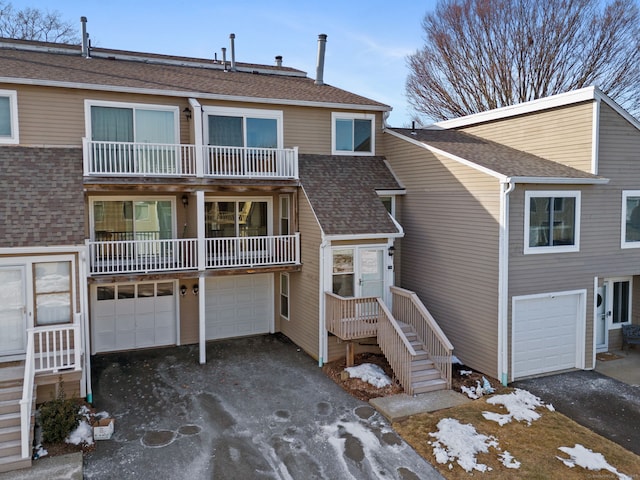 view of front of house with a garage, driveway, a balcony, and a shingled roof