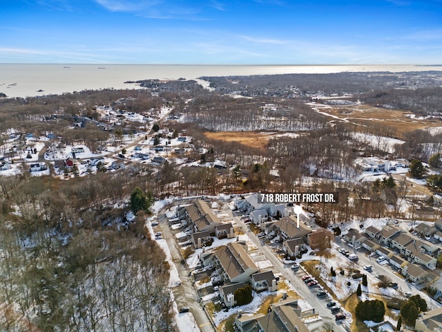 snowy aerial view featuring a water view and a residential view