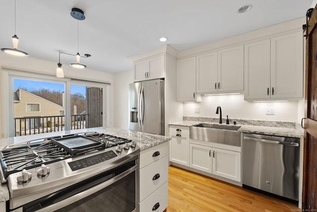 kitchen with stainless steel appliances, light stone counters, hanging light fixtures, and white cabinetry