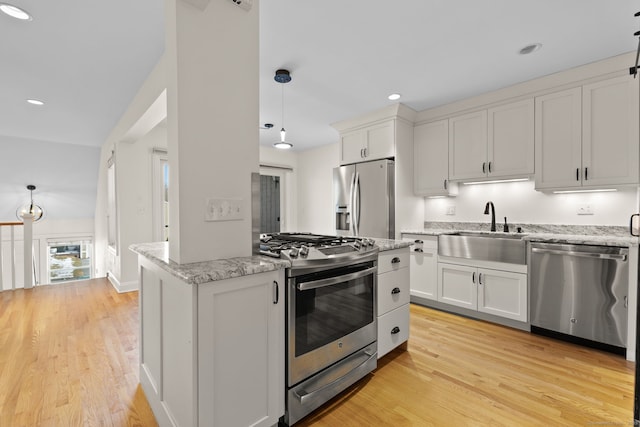 kitchen featuring stainless steel appliances, hanging light fixtures, a sink, and white cabinetry