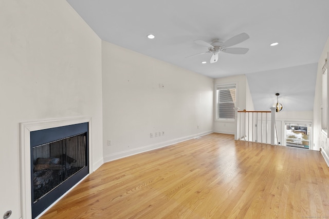 unfurnished living room with light wood-type flooring, a fireplace, baseboards, and recessed lighting