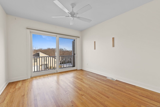 spare room with ceiling fan, light wood-type flooring, visible vents, and baseboards