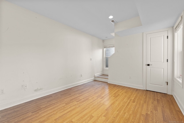 empty room with light wood-style floors, baseboards, and visible vents