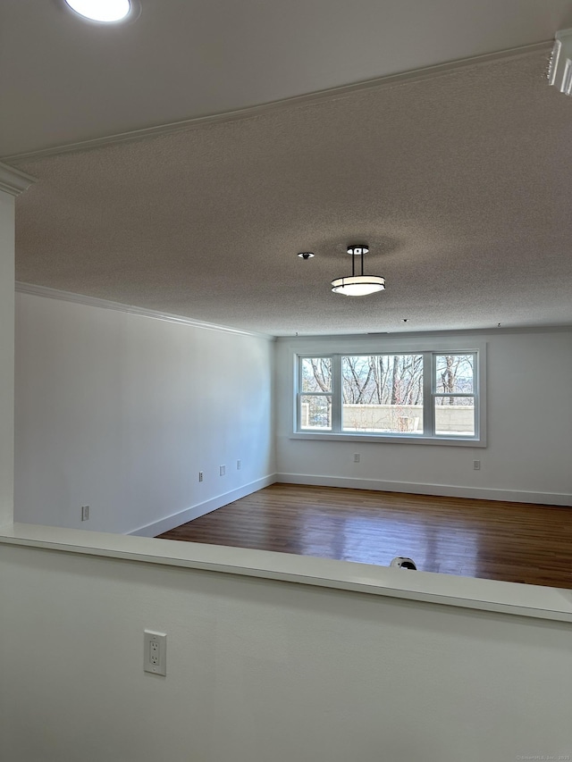 unfurnished room featuring a textured ceiling, baseboards, and wood finished floors