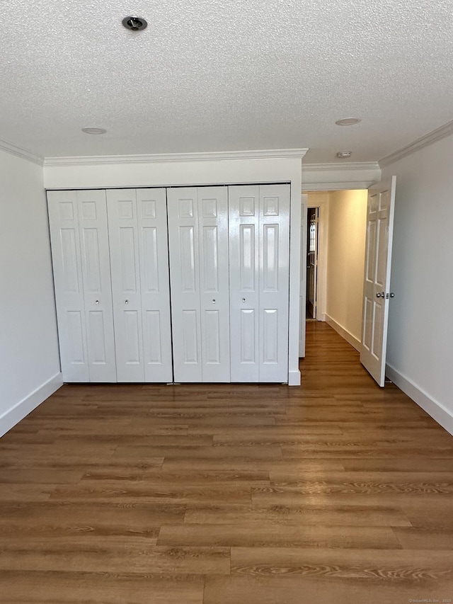 unfurnished bedroom with a closet, crown molding, and wood finished floors