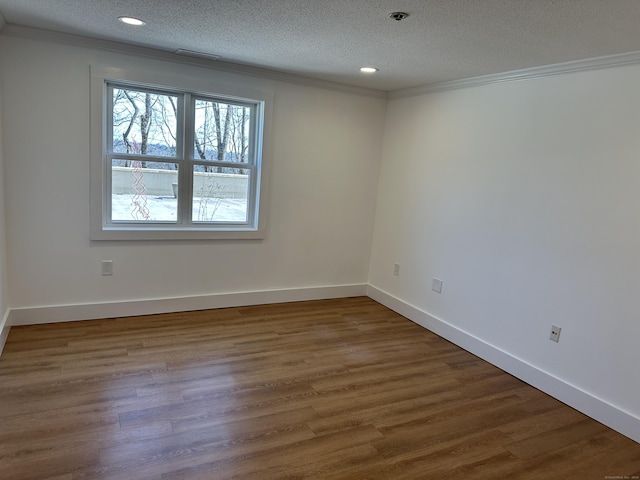 empty room with baseboards, wood finished floors, a textured ceiling, and ornamental molding