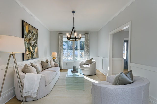 living area with crown molding, wainscoting, a notable chandelier, and a healthy amount of sunlight