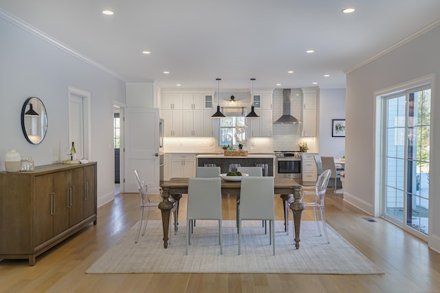 dining space with ornamental molding, a wealth of natural light, and light wood-style floors