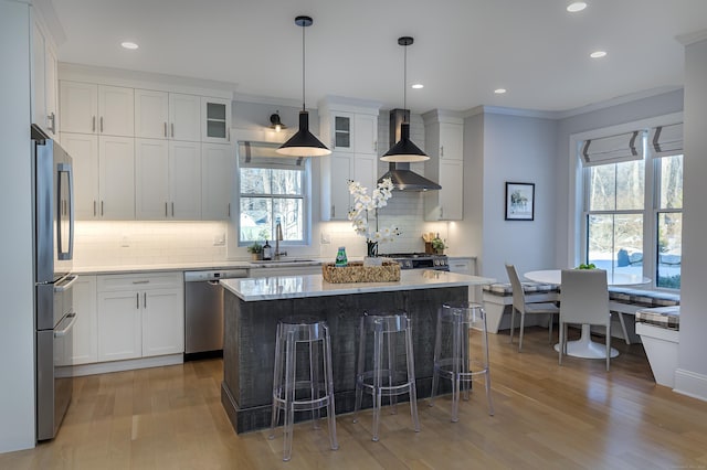 kitchen with glass insert cabinets, appliances with stainless steel finishes, a center island, white cabinetry, and a sink