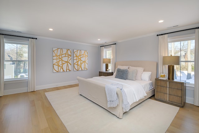 bedroom with ornamental molding, multiple windows, and wood finished floors