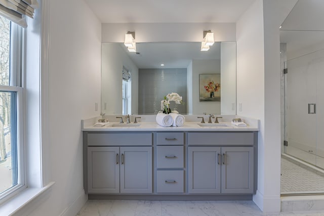 full bath with double vanity, marble finish floor, a shower stall, and a sink