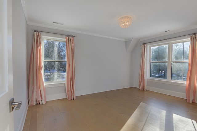 spare room featuring visible vents, crown molding, and light wood-style flooring