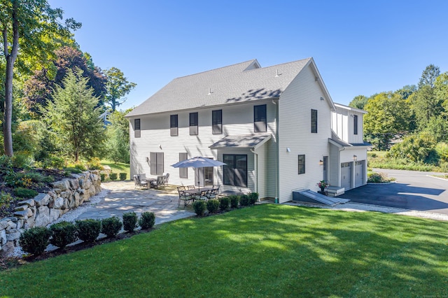 back of house featuring a garage, a patio, driveway, and a lawn